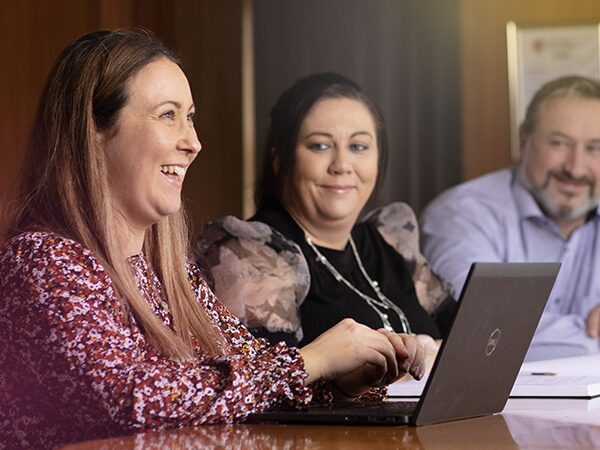 Some ABP workers at a conference table smiling with laptop